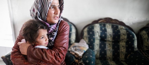 Una donna siriana preoccupata mentre protegge una bambina
