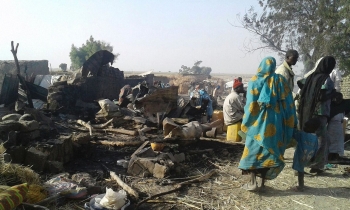 People stand next to site of bombing in Rann, northeast Nigeria.