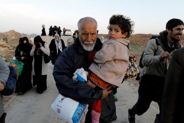An Iraqi man and his granddaughter fleeing their home in Mosul while Iraqi forces battle with ISIS on March 8, right before the wedding suicide attack.  
