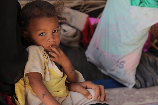 Un bambino yemenita si morde le dita e guarda verso la fotocamera