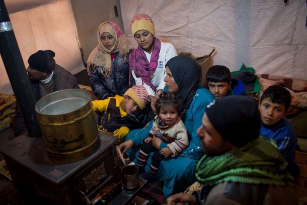 A Syrian refugee family gathered around a stove inside their shelter in Lebanon’s Bekaa Valley.