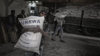 A Palestinian refugee carries a bag of flour at a UNRWA food distribution centre