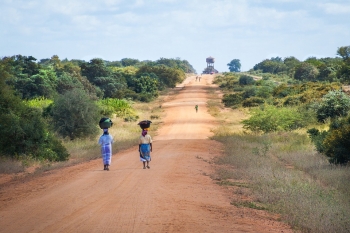 African women walking on a sand road in Mapai, Mozambique 