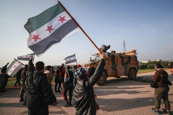 Siriani che protestano di fronte a un mezzo militare turco