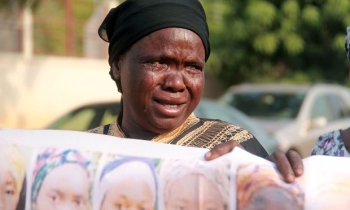  A Nigerian woman, the mother of a girl abducted by Boko Haram Islamists, cries as she displays a banner showing images of the missing girls
