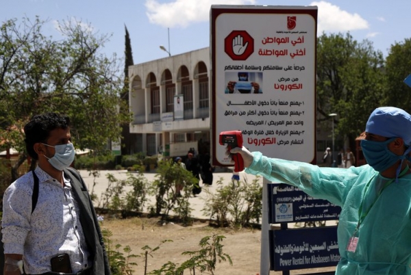 Operatori sanitari yemeniti misurano la temperatura di un uomo utilizzando un termometro a infrarossi all’ingresso di un ospitale locale