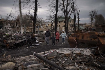 Una famiglia ucraina cammina tra le macerie della sua città